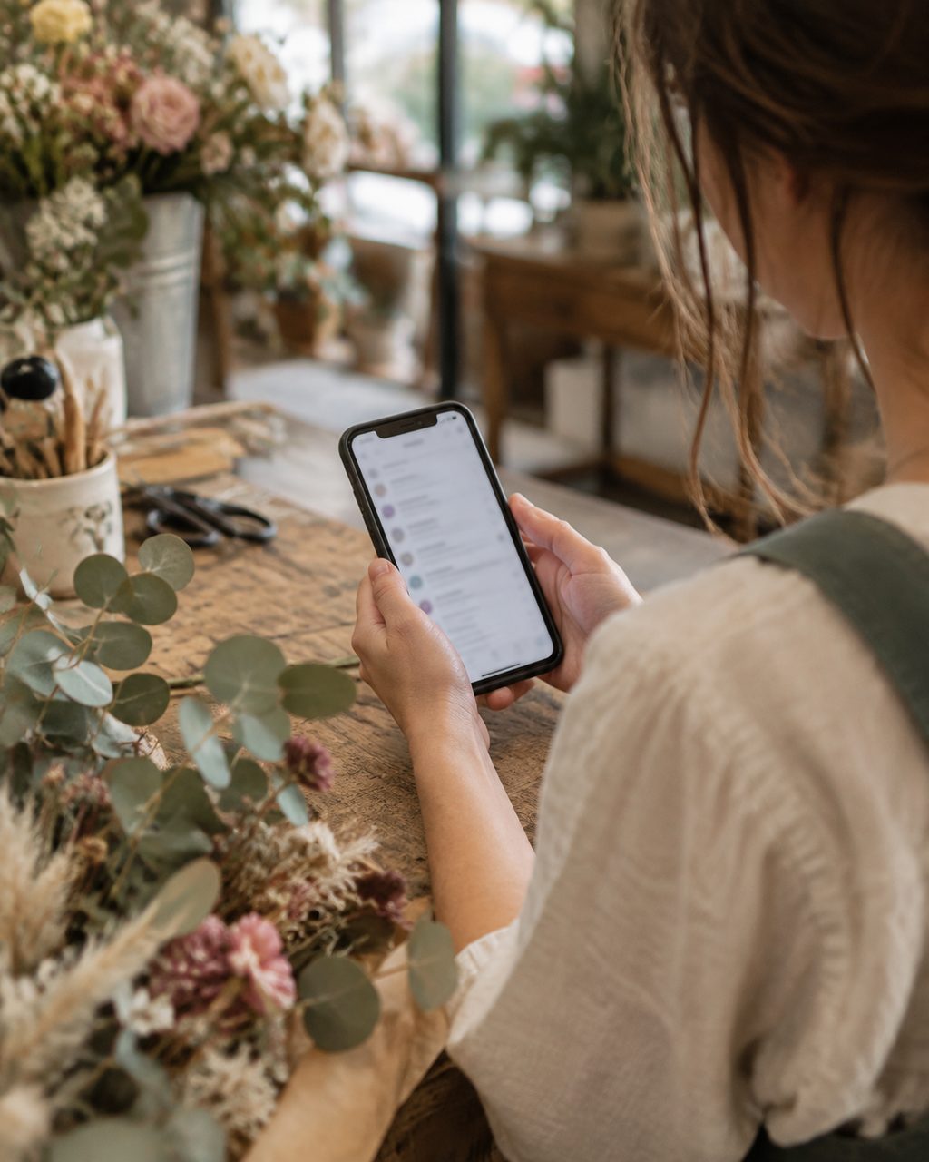 Florist checking business email on a phone at the shop counter