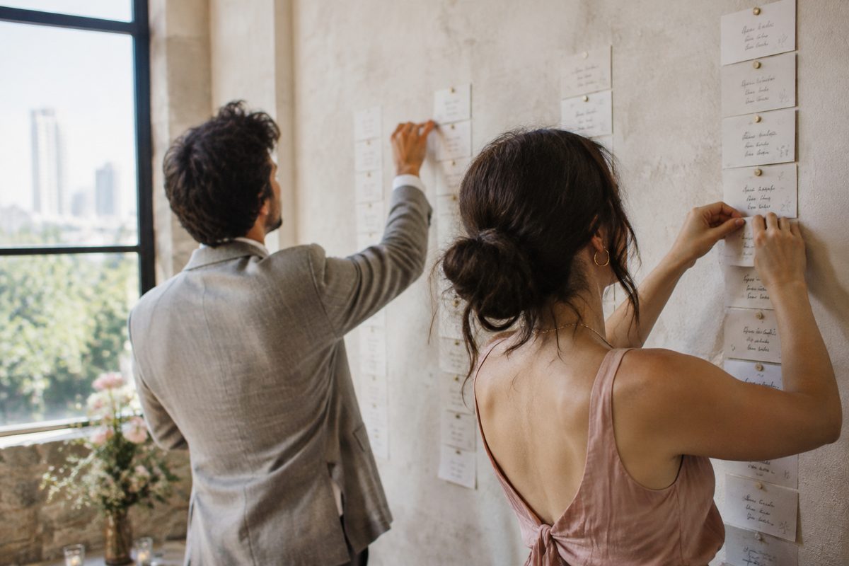 Two people sorting domain name candidates on paper cards pinned to a wall